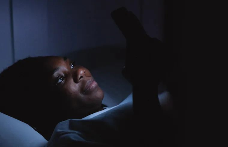 Pessoa deitada na cama trancando a porta blindada com fechadura digital